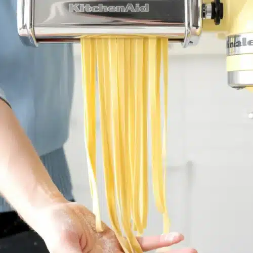 Homemade fresh pasta made with flour, eggs, and olive oil on a wooden surface.