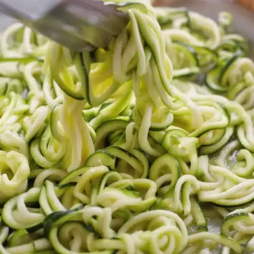 Delicious zucchini noodles topped with garlic, basil, and parmesan in a skillet.