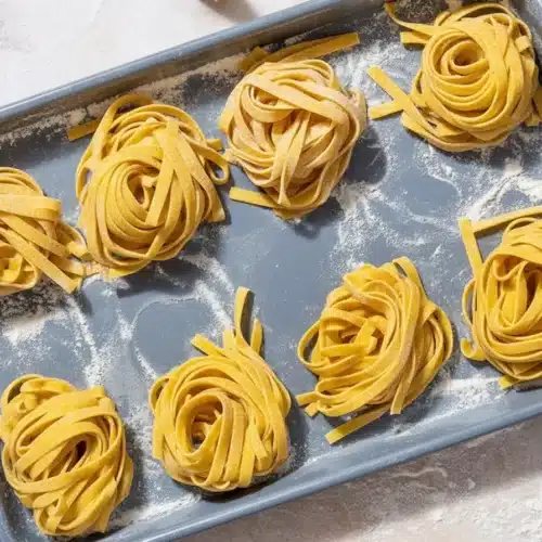 Fresh pasta dough made from flour and eggs on a clean work surface.